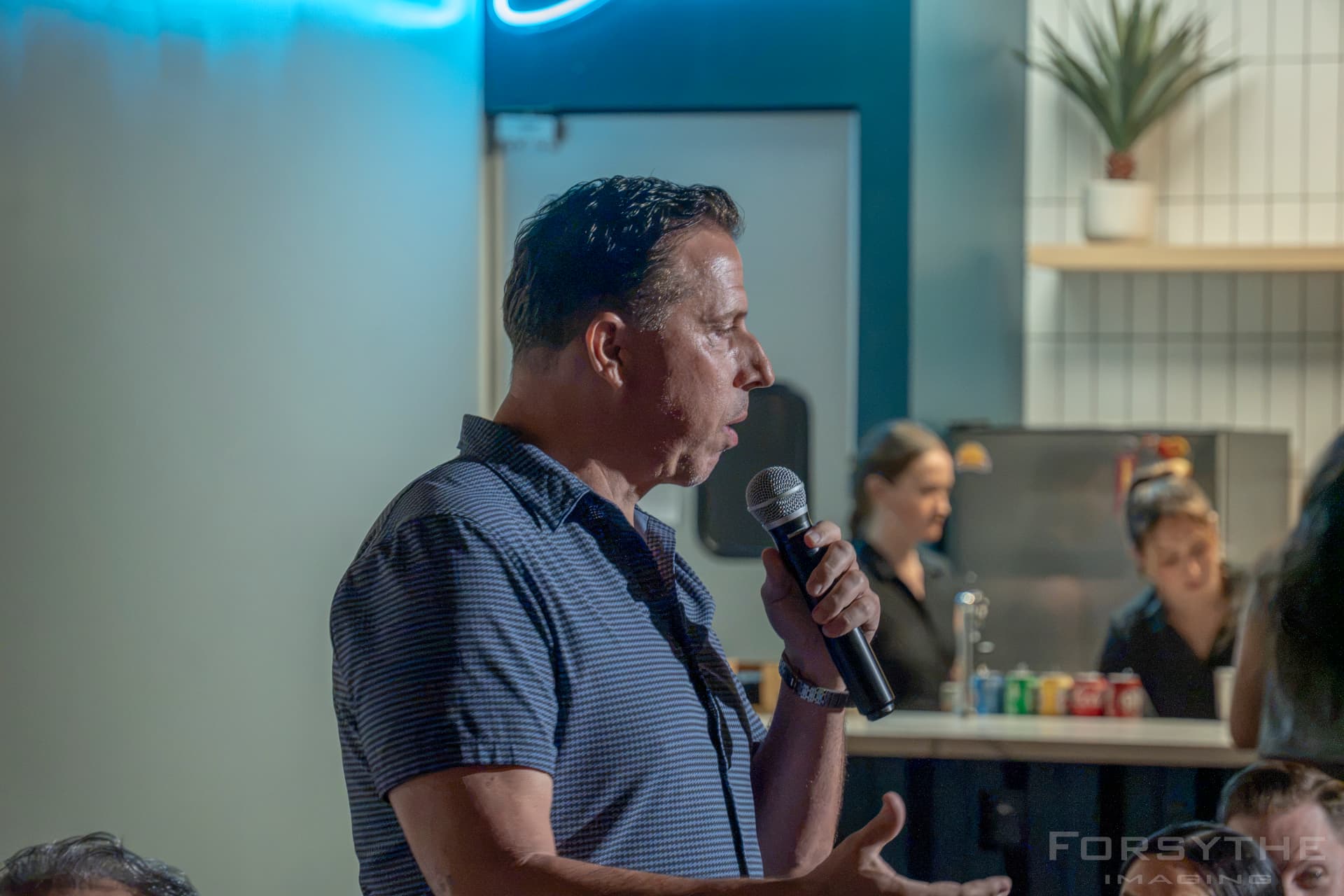Comedian on the mic under the blue neon glow