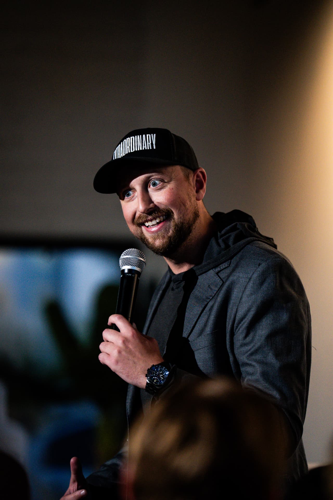 Forbes Shannon on the mic, mid-laugh, working a live room