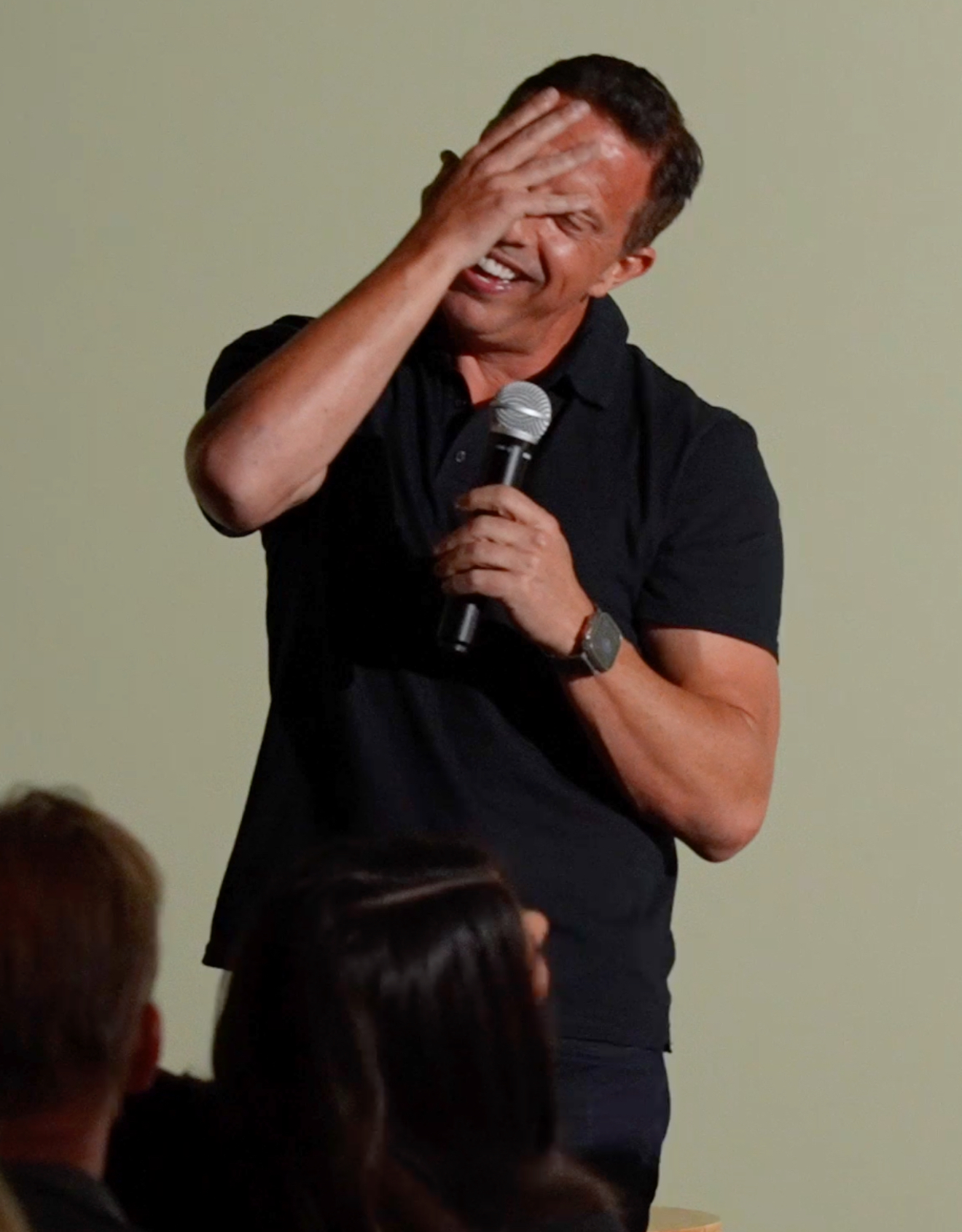 Comedian laughing with a hand over his face after a joke lands sideways